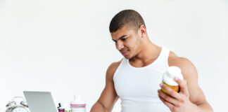 happy-young-sportsman-holding-sport-nutrition-using-laptop